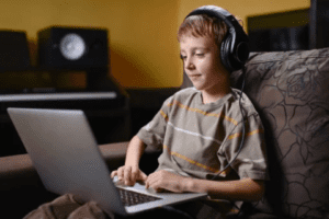 A boy with headphones on using a laptop.