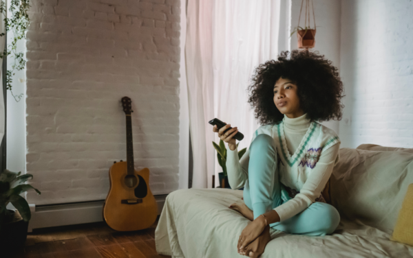 A woman sitting on the bed holding a remote control.