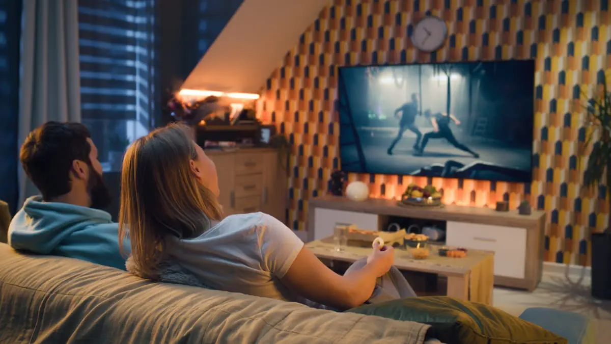 Couple watching TV on couch at home.