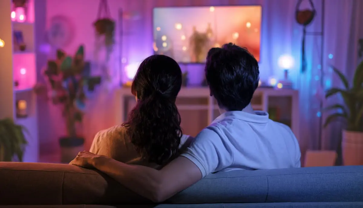 Couple watching TV on couch at night.