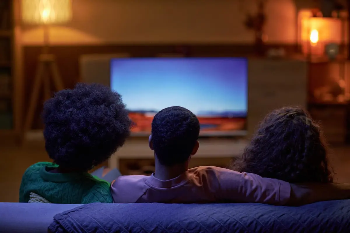 Three people watching TV on a couch.